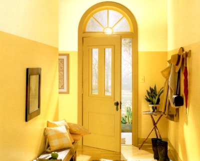 Deep yellow front door in a hallway painted in different shades of the same hue