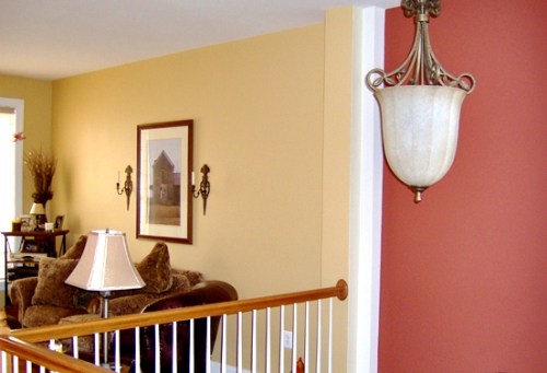 Bright yellow living room wall color is juxtaposed with the bold red foyer