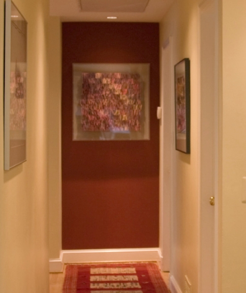 Brick red accent wall at the end of a hallway painted ivory