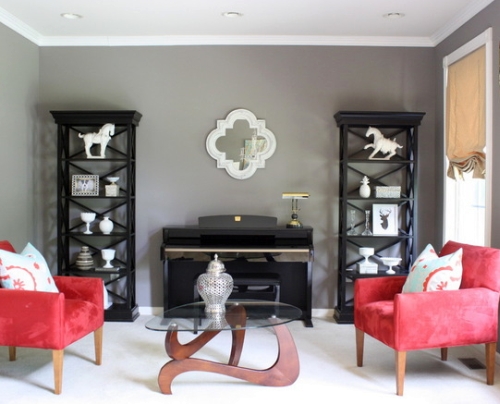 Gray living room walls are offset by the black shelves and red chairs