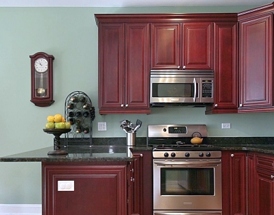 Red stained kitchen cabinets with sage green walls