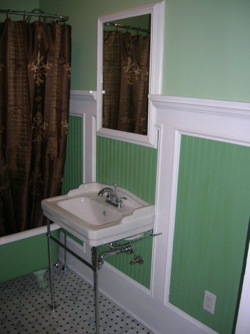 Bathroom painted with different shades of green and decorated with brown