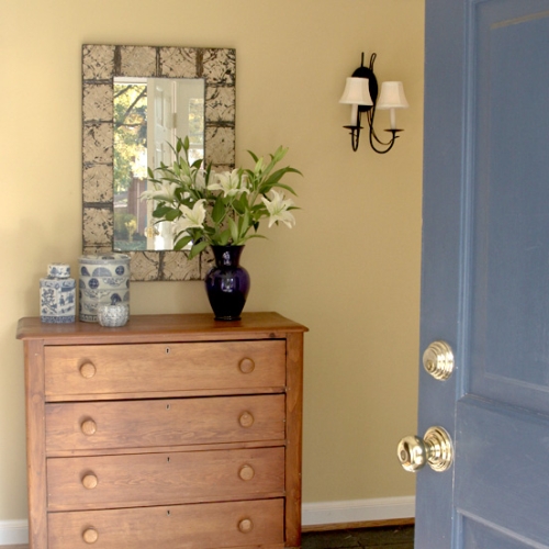 Soft yellow paint color on the wall complemented by a blue door