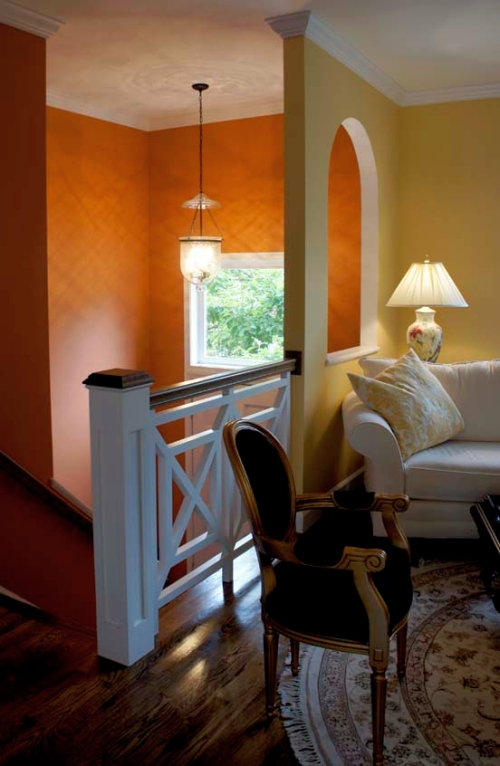 Bold orange foyer wall color contrasts with the sunny yellow living room